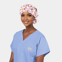 woman wearing a light blue scrup top and a pink bouffant scrub hat with cats on it