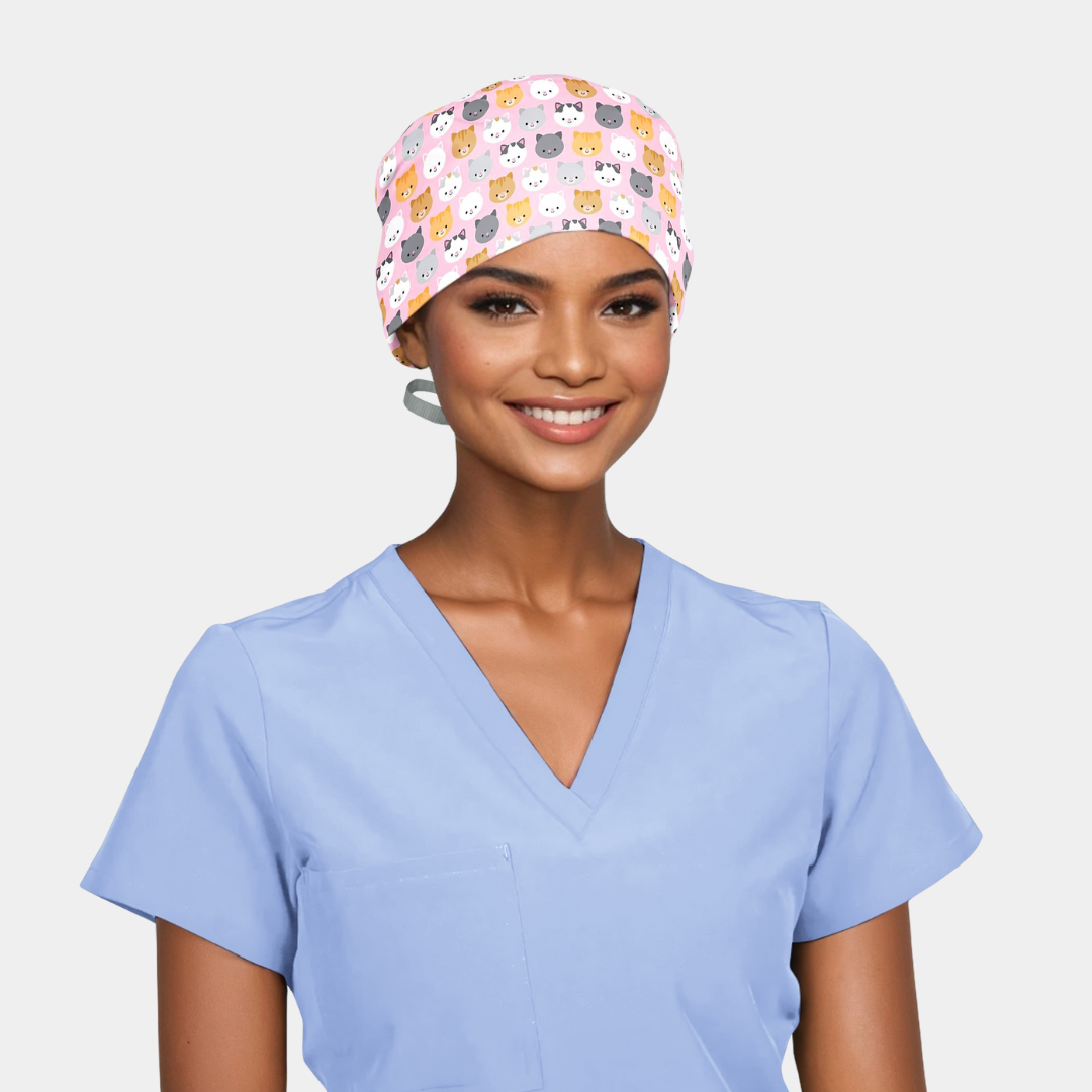 person wearing a light blue scrub top and a pink scrub hat with cute cats on it