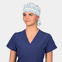 woman wearing a navy blue scrub top and a ponytail scrub cap with deer and blue vines on a light blue background