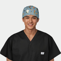 man wearing a black scrub top with a halloween scrub hat that has ghost, pumpkins and cats on a blue background