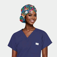 woman wearing a navy blue scrub top and a bouffant scrub cap with Frida Kahlo and flowers on it