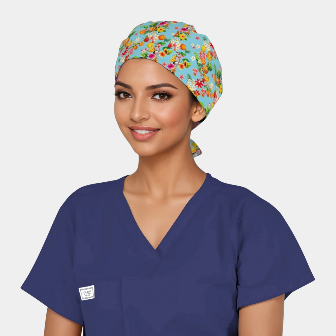 Woman wearing a colorful floral scrub cap and navy blue scrub top on a plain background