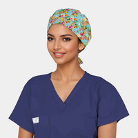 Woman wearing a colorful floral scrub cap and navy blue scrub top on a plain background