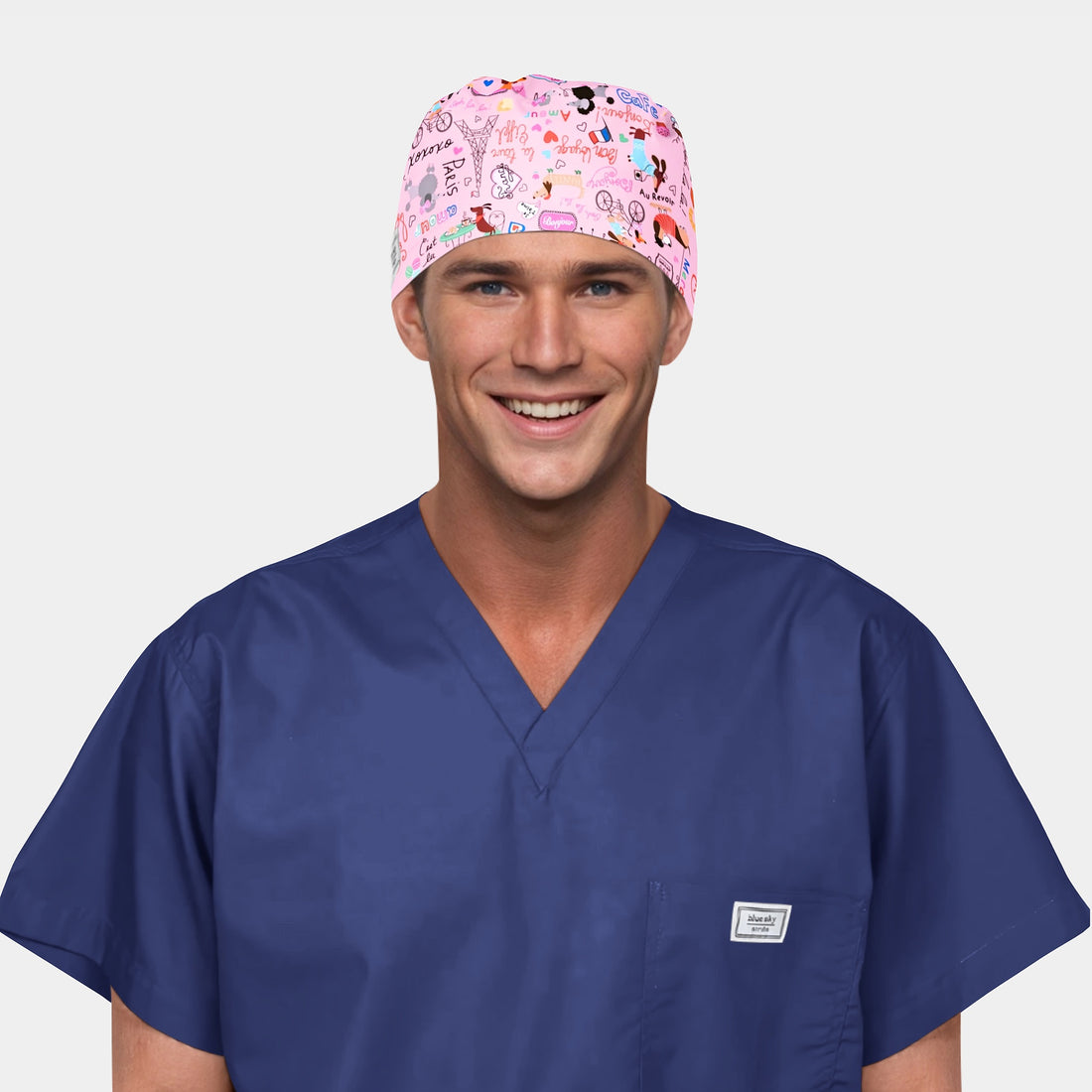 man wearing a navy blue scrub top and a pink scrub hat with parisian symbols on it