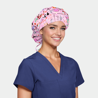woman wearing a navy blue scrub top and a pink bouffant hat with paris icons on it