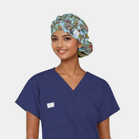 woman wearing a navy scrub top and a bouffant scrub that is light blue with flowers, plants and butterflies on it.