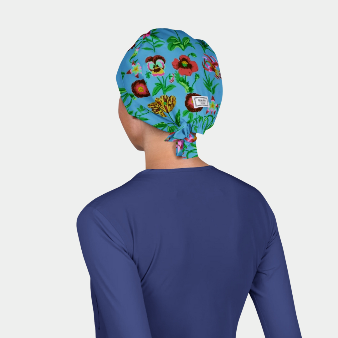 Person wearing a colorful floral-patterned scrub cap on a plain background