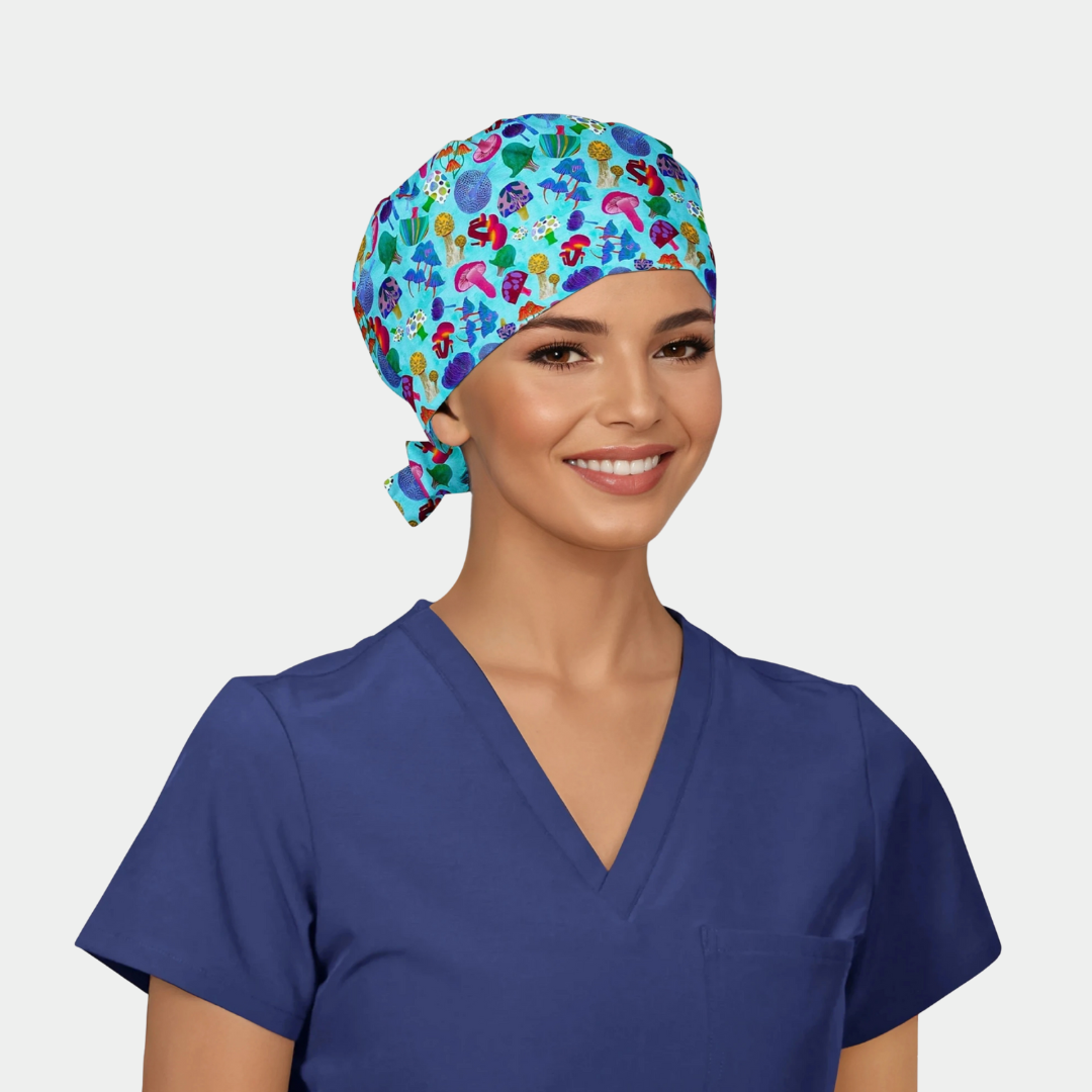 Person wearing a colorful patterned scrub cap with mushrooms on it and blue scrub top on a plain background