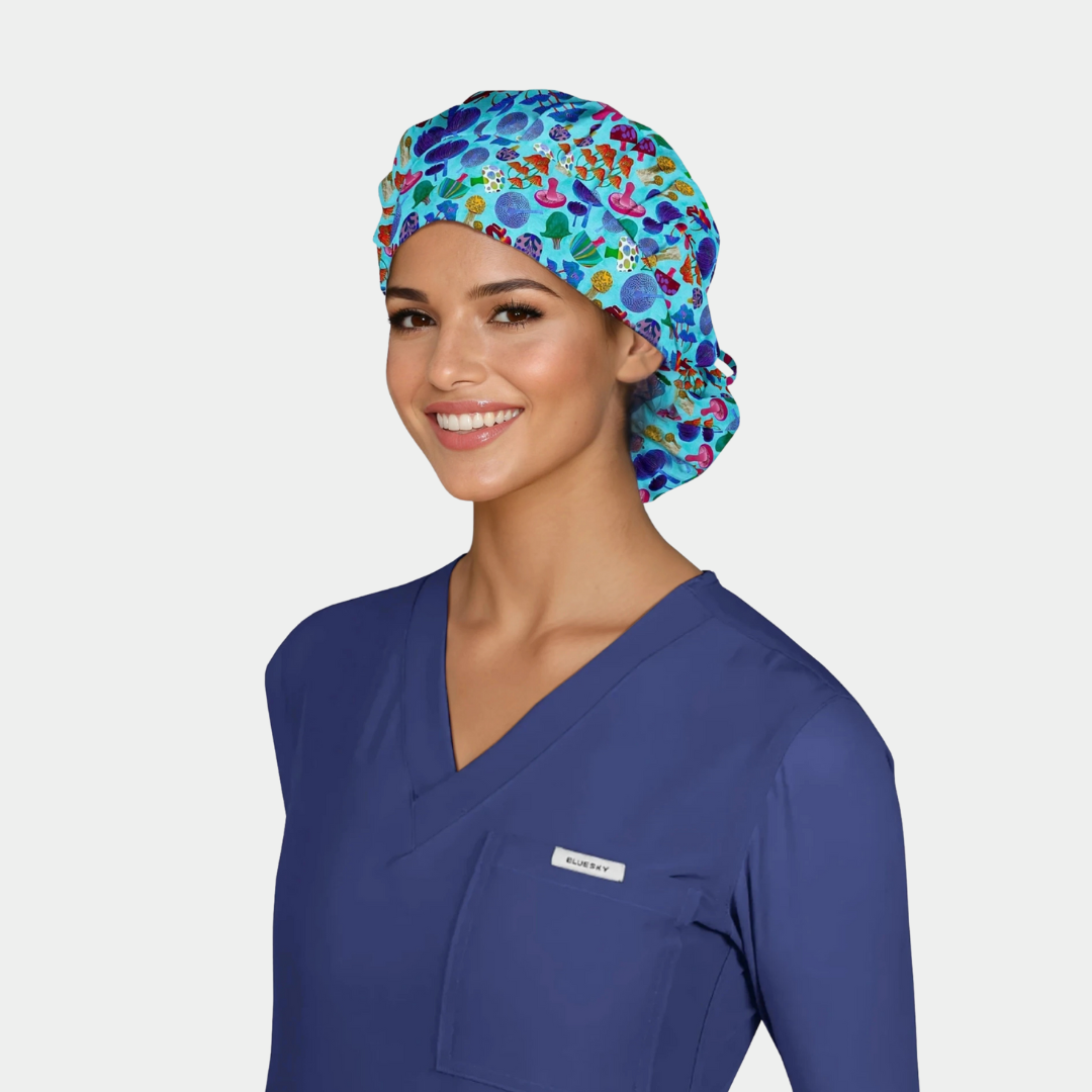 woman wearing a bouffant scrub hat with mushrooms on it and navy blue scrub top on a white background