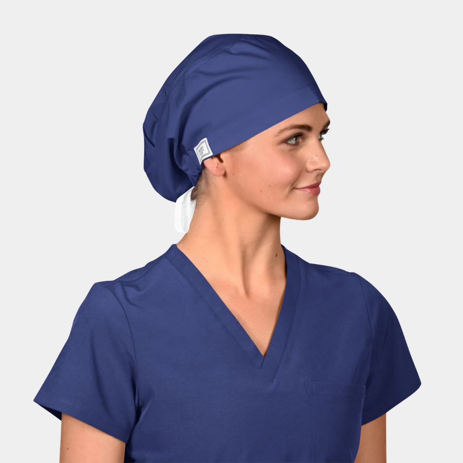 Person wearing a blue scrub top and matching scrub cap on a light gray background