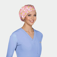 Person wearing a light blue scrub top and a pink scrub cap with pickleball designs on a plain background