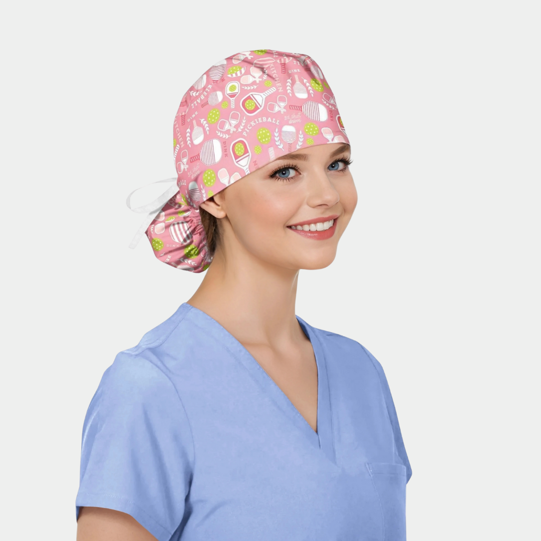 Person wearing a pink pickleball themed scrub cap with a pattern on a plain background
