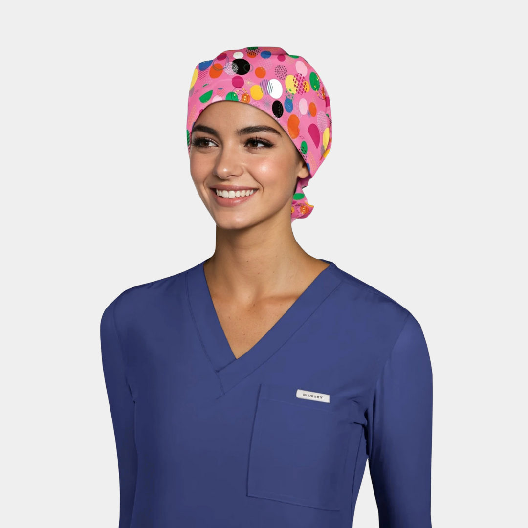 Person wearing a colorful polka dot scrub cap and blue scrub top on a light gray background