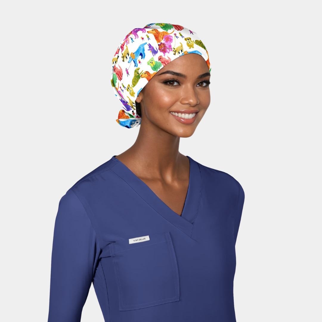 Woman wearing a surgical cap with dogs on it and blue scrub top on a white background