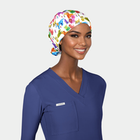 Woman wearing a surgical cap with dogs on it and blue scrub top on a white background