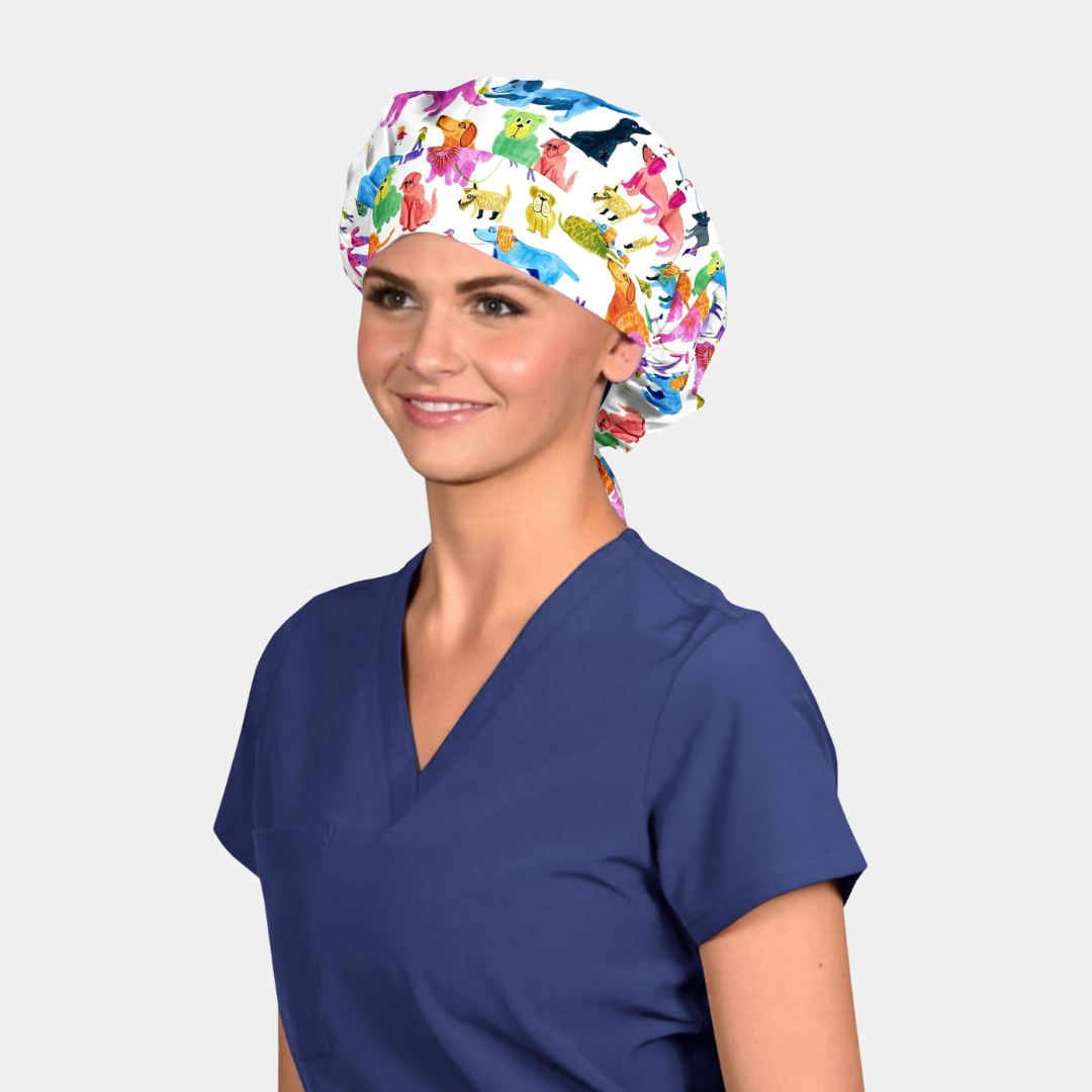 Person wearing a bouffant scrub cap with dogs on it and navy blue scrub top on a white background