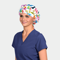 Person wearing a bouffant scrub cap with dogs on it and navy blue scrub top on a white background