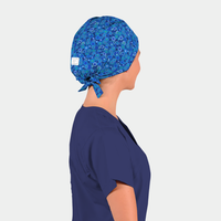 Person wearing a blue scrub cap with a floral pattern on a plain background