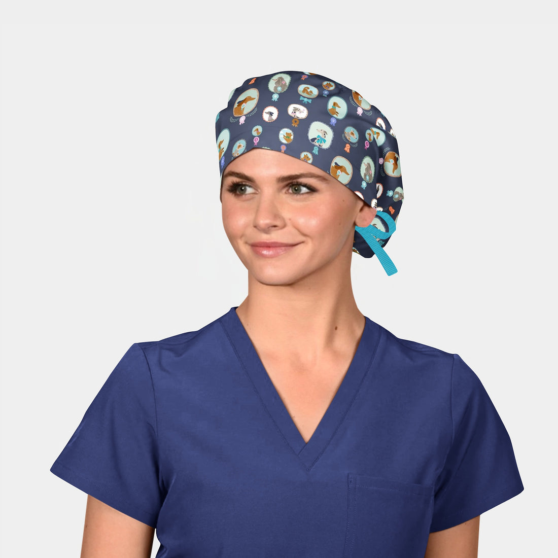 Person wearing a blue scrub top and patterned scrub cap on a plain background