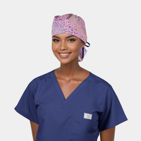 woman wearing a navy blue scrub top and a pink ponytail surgical cap with stars on it on a white background.