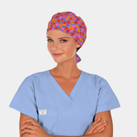 Person wearing a colorful polka dot scrub cap and light blue scrub top on a white background