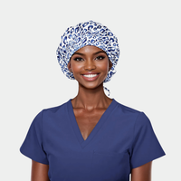 Woman wearing a blue scrub top and leopard print surgical cap on a light gray background