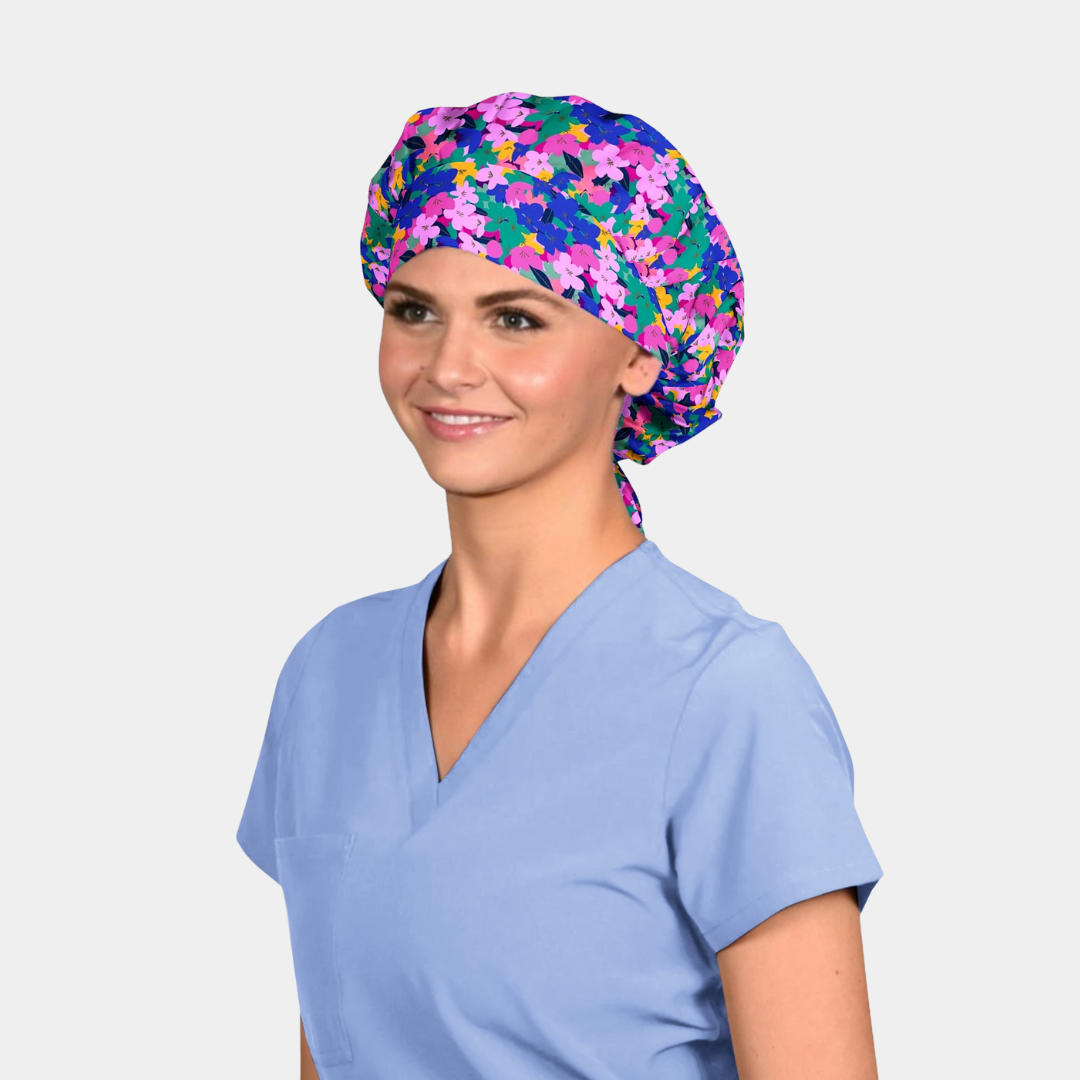 woman wearing a floral bouffant scrub hat with a light blue scrub top on a white background
