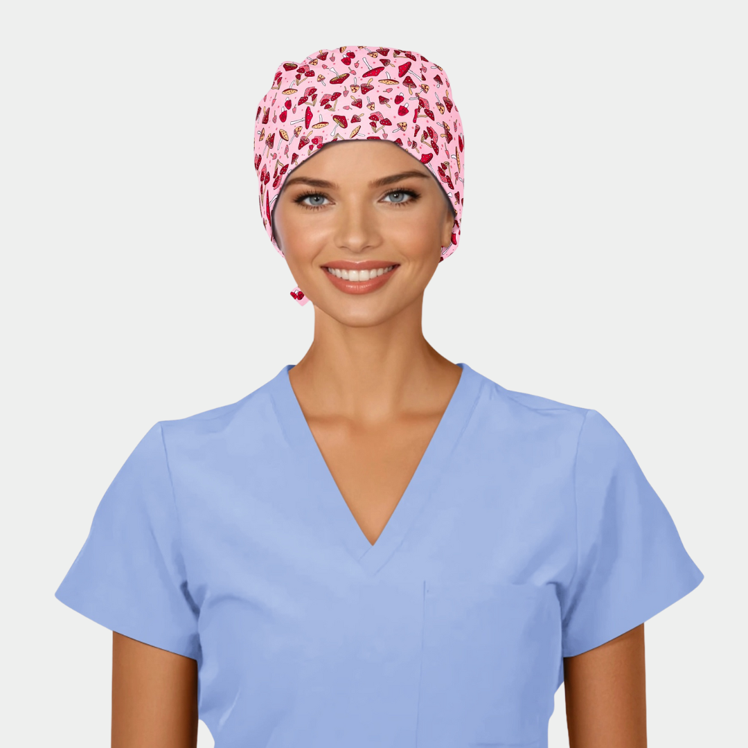 Woman wearing a light blue scrub top and a pink scrub cap with mushrooms on it on a white background