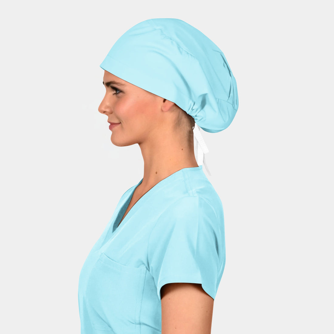 Woman wearing a light blue scrub top and matching scrub hat on a plain background