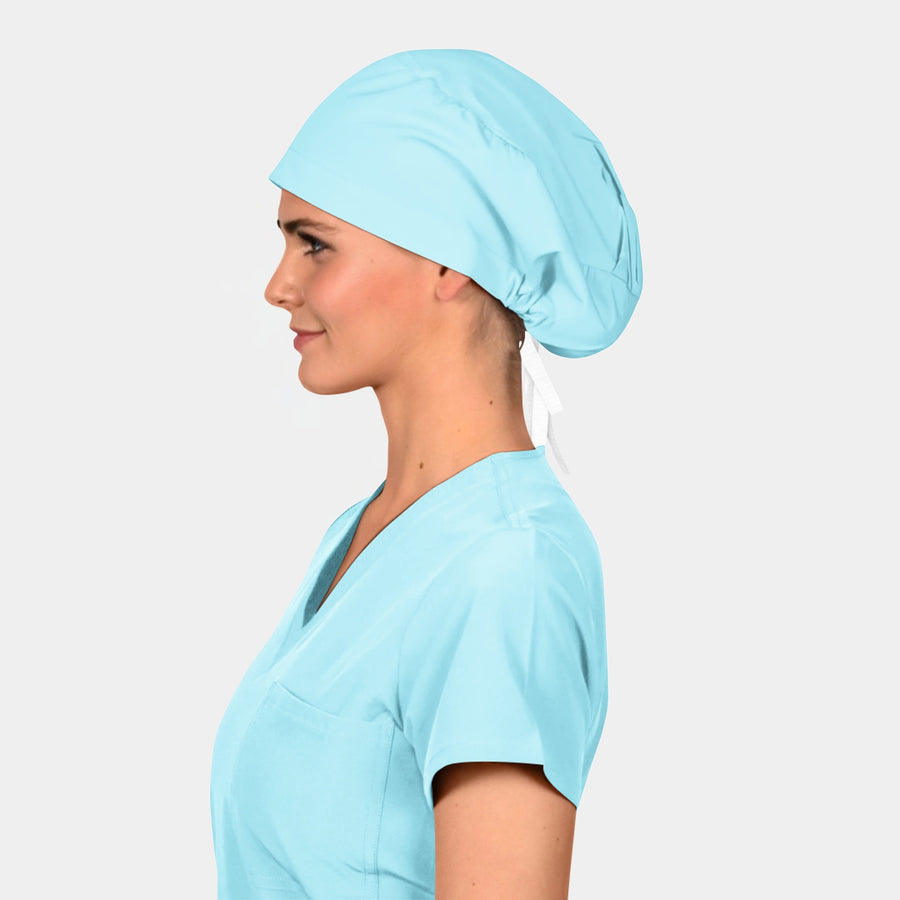 Woman wearing a light blue scrub top and matching scrub hat on a plain background
