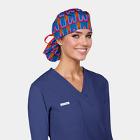 Woman wearing a blue scrub set with a colorful scrub cap on a light gray background