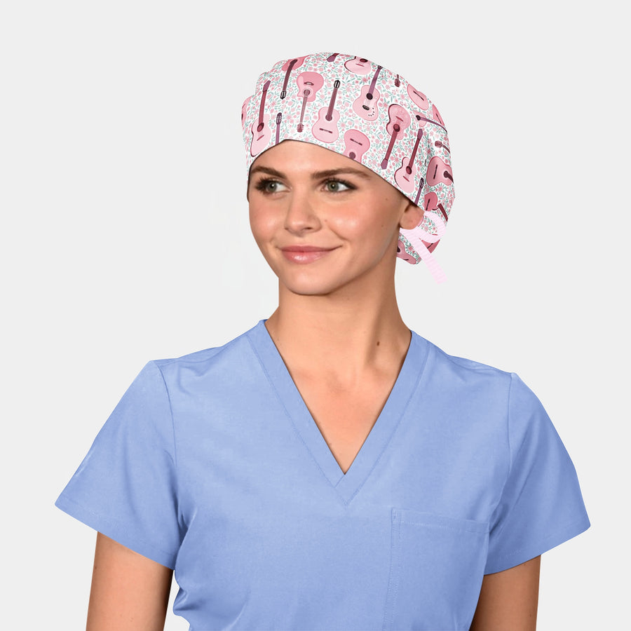 woman wearing a surgical hat with pink guitars on it and a light blue scrub top on a white background