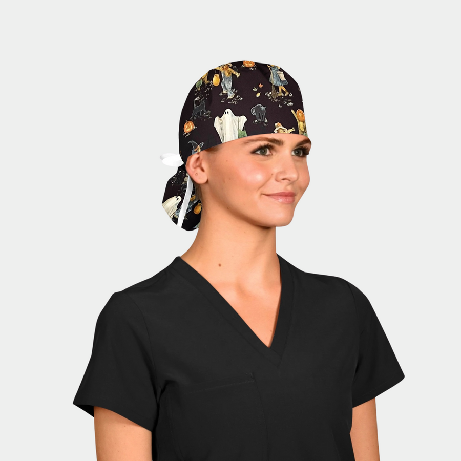 woman in a black scrub top with a halloween ponytail scrub cap on that has ghosts, scarecrows and cats