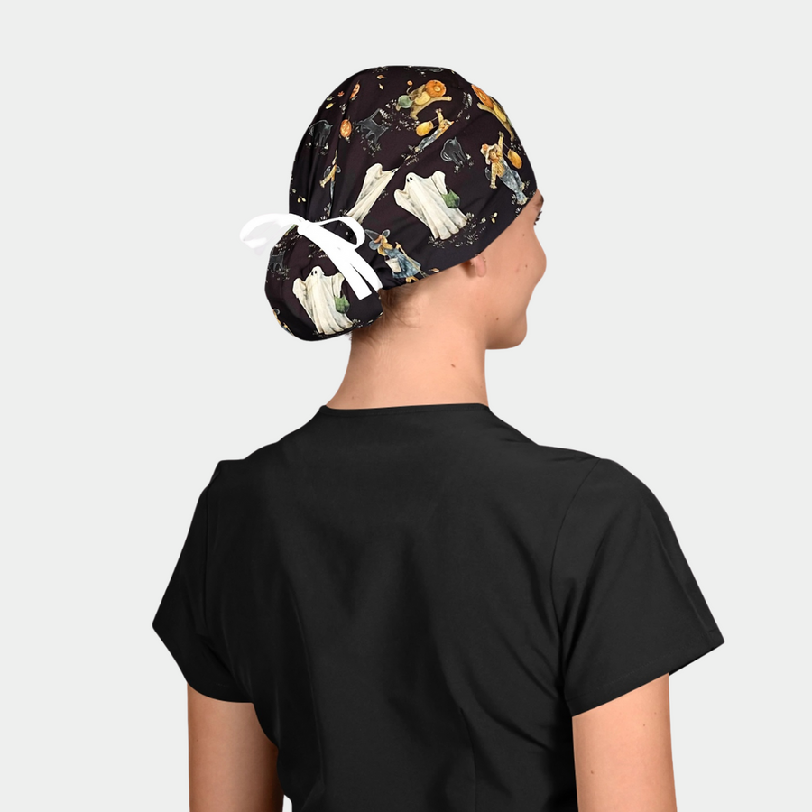 woman wearing a black scrub top and a halloween surgical cap that has ghosts, scarecrows and cats on it.