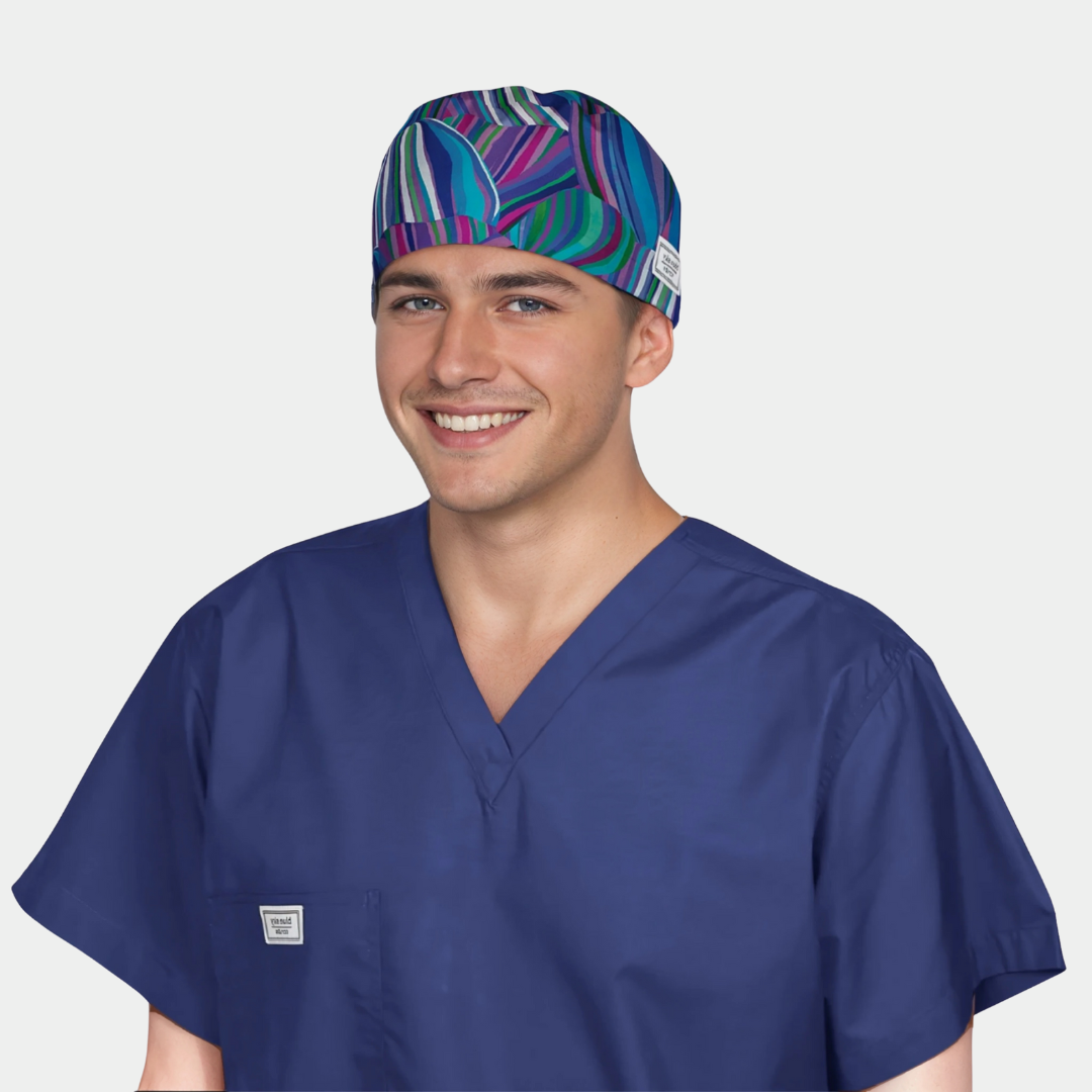 man wearing a navy blue scrub top and a scrub hat with a wavy pattern of blues and purples.