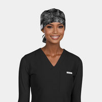 woman wearing a halloween themed surgical cap with white spiderwebs on a black background and a black scrub top