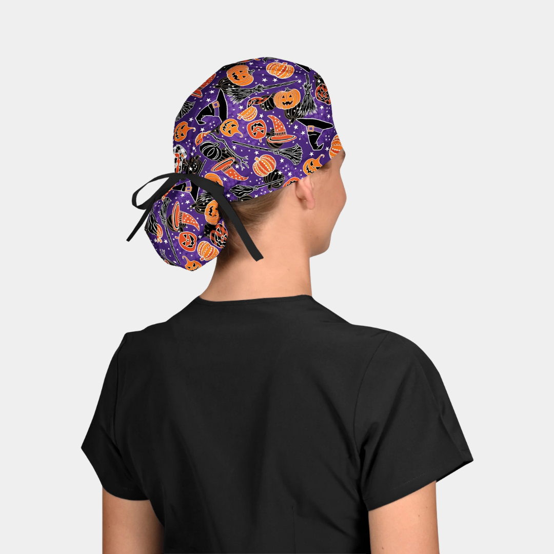 Person wearing a Halloween-themed scrub cap with black scrubs on a light grey background