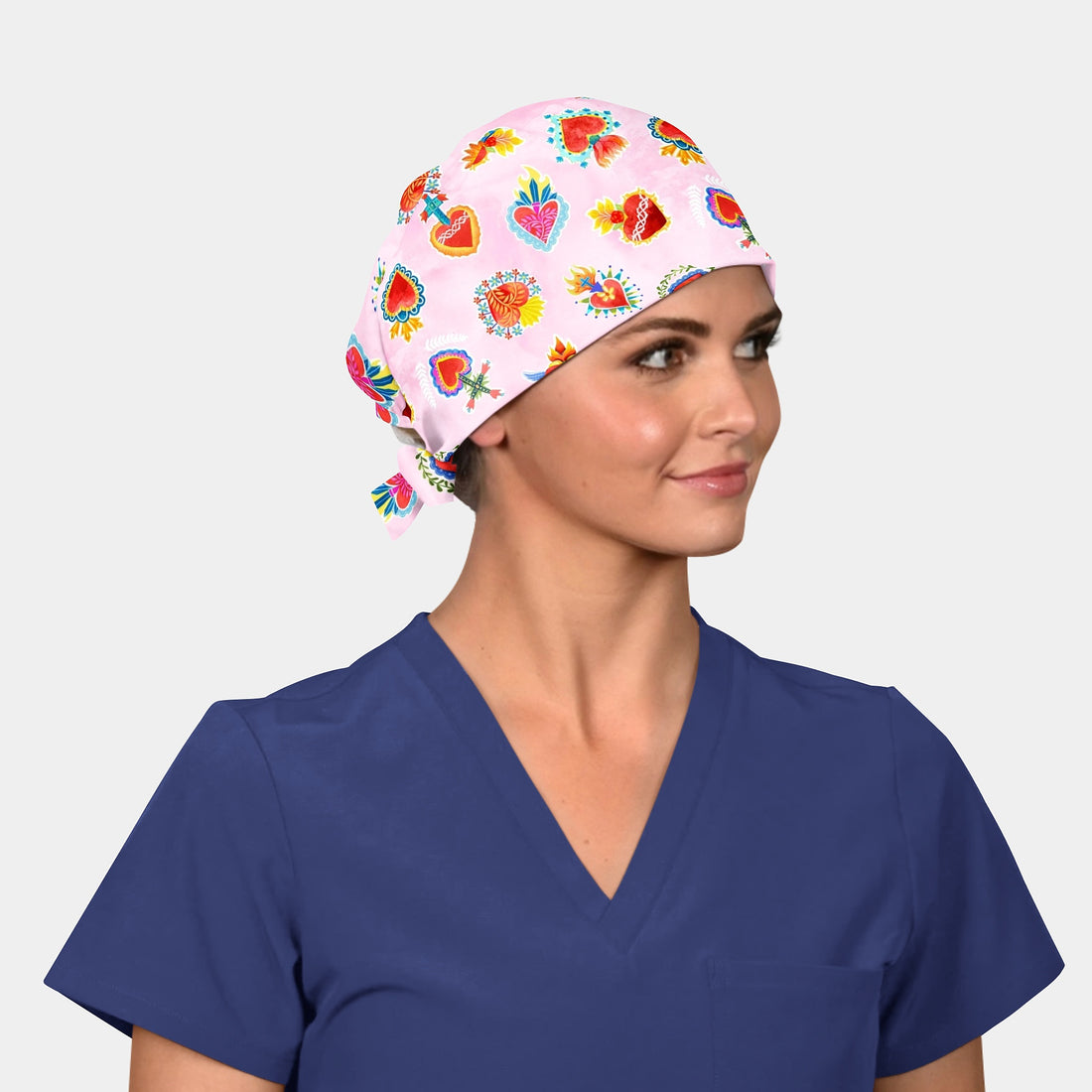  light pink surgical hat with a pattern of hearts and other symbols.
