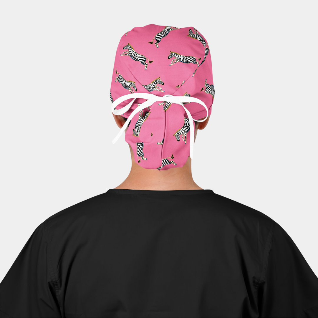 woman wearing a black scrub top and a pink ponytail scrub cap with zebras on it